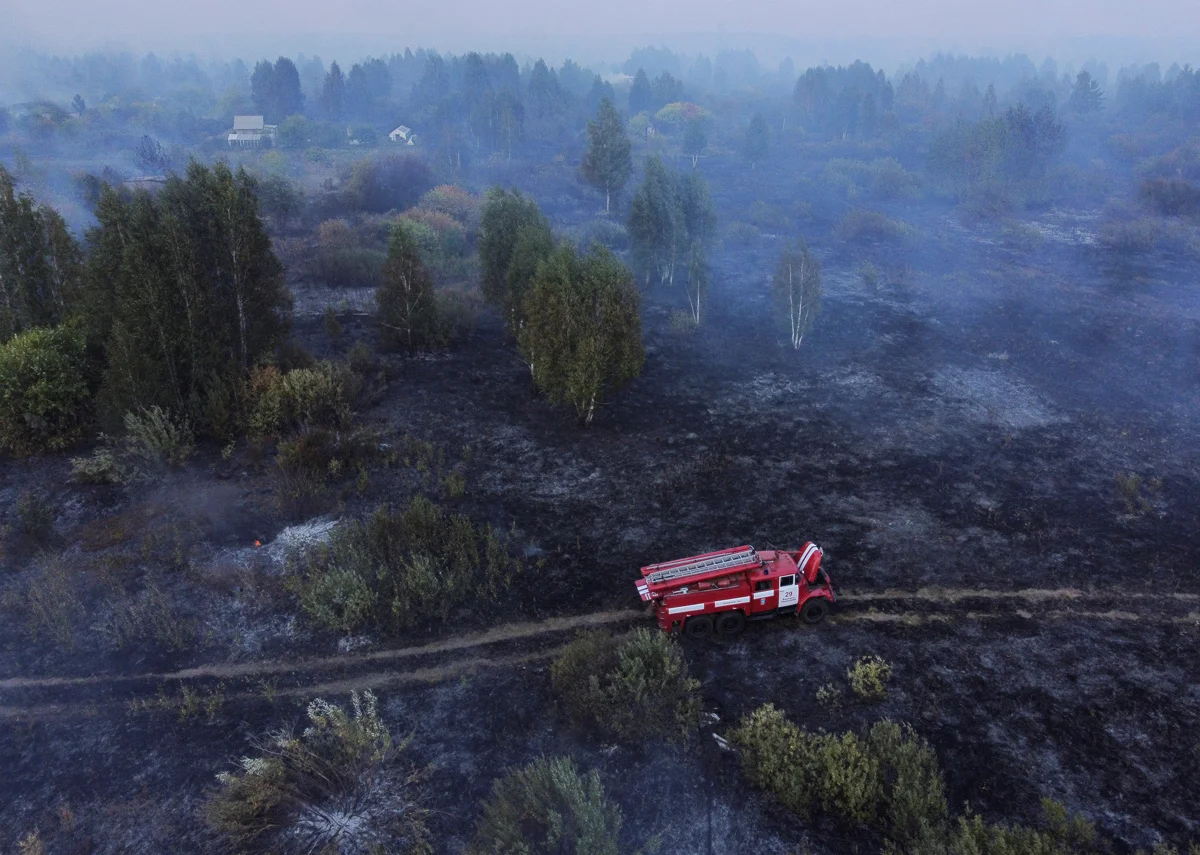 Вид на пожарный автомобиль среди сгоревшей травы на территории, пострадавшей от лесного пожара в Свердловской области, 25 августа 2021 года. Фото: Алексей Малгавко / Reuters / Scanpix / LETA