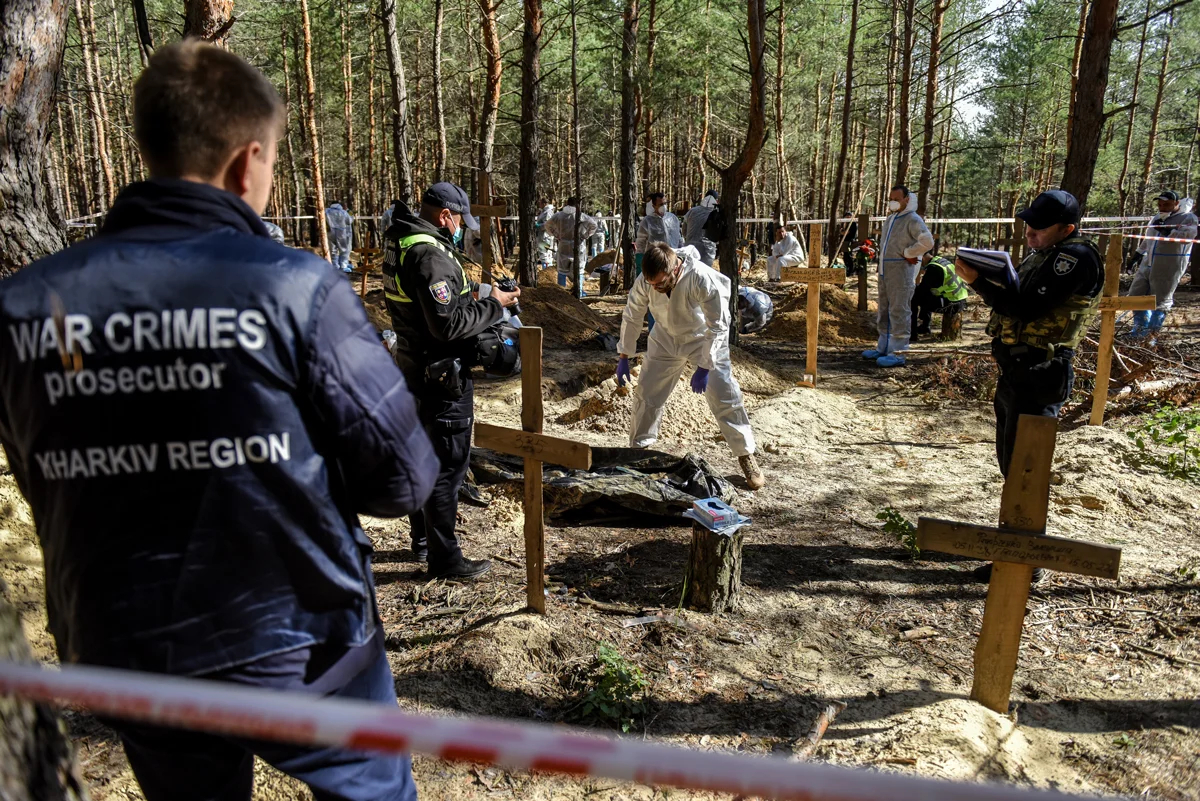 Сотрудники прокуратуры по военным преступлениям во время эксгумации на кладбище в Изюме, Харьковская область, 22 сентября 2022 года. Фото: Oleg Petrasyuk / EPA