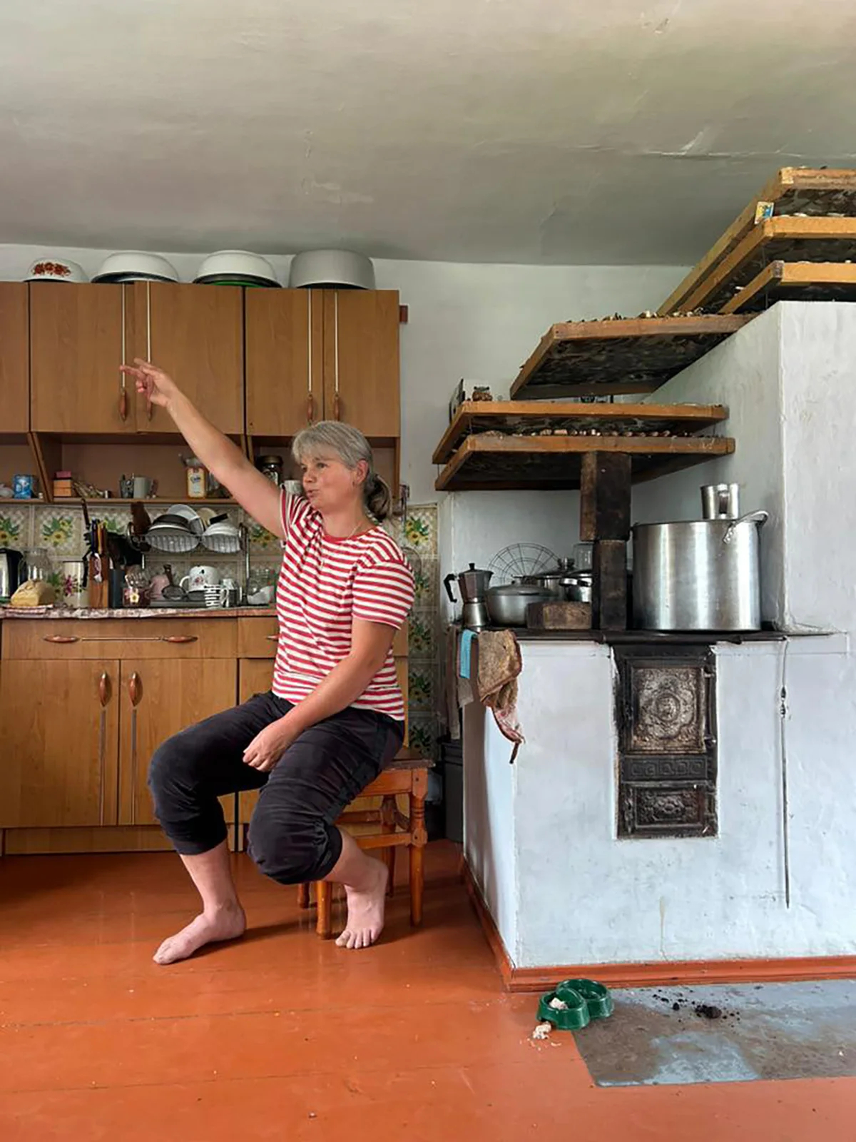 Галина Зеленчук в летней кухне рядом с печью, где печется хлеб, а сверху сушатся грибы. Фото автора