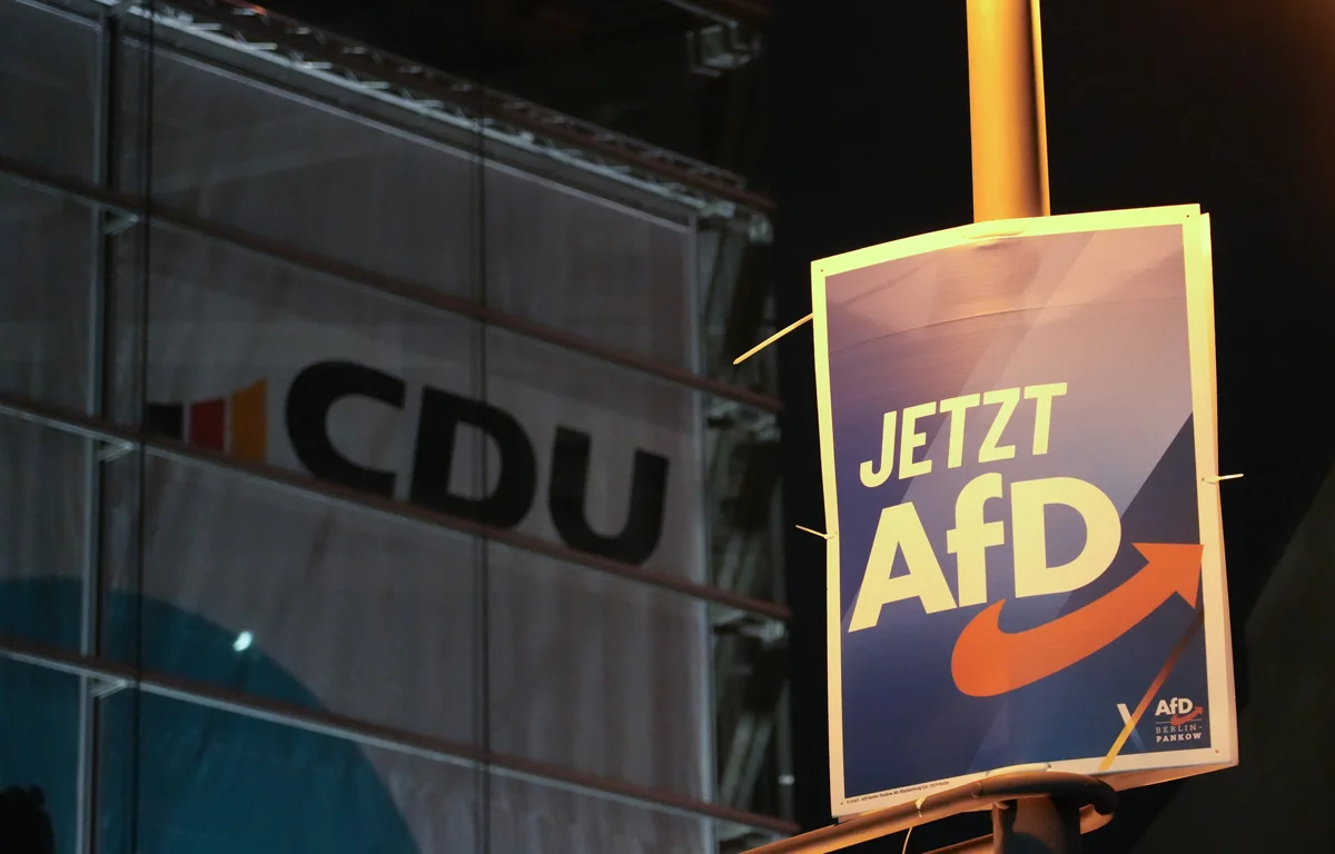 Плакат AfD на фоне логотипа партии CDU в Берлине, 30 января 2025 года. Фото: Manuel Genolet / dpa / picture-alliance / Scanpix / LETA