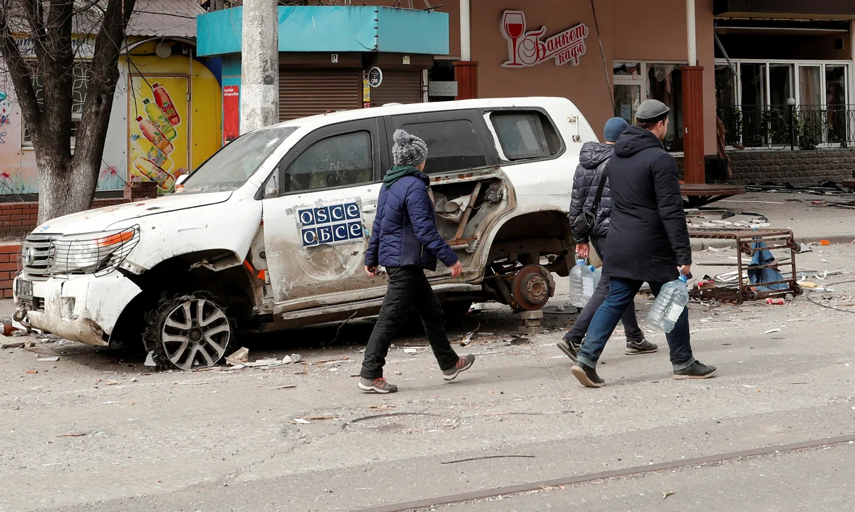 Люди проходят мимо повреждённого автомобиля ОБСЕ в Мариуполе, Украина, 1 апреля 2022 года. Фото: Александр Ермоченко / Reuters / Scanpix / LETA
