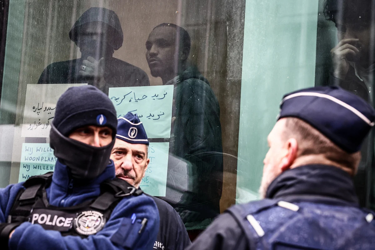 Бельгийские полицейские на фоне мигрантов, Брюссель, 14 марта 2023 года. Фото: Stephanie Lecocq / EPA