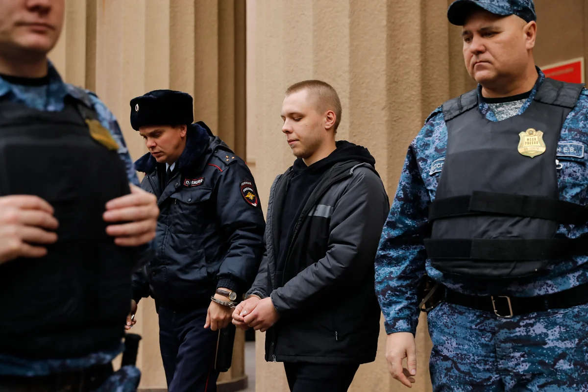 Никита Журавель (в центре) выходит в сопровождении полицейских из суда после слушания дела о государственной измене, Волгоград, 14 ноября 2024 года. Фото: AP Photo / Scanpix / LETA